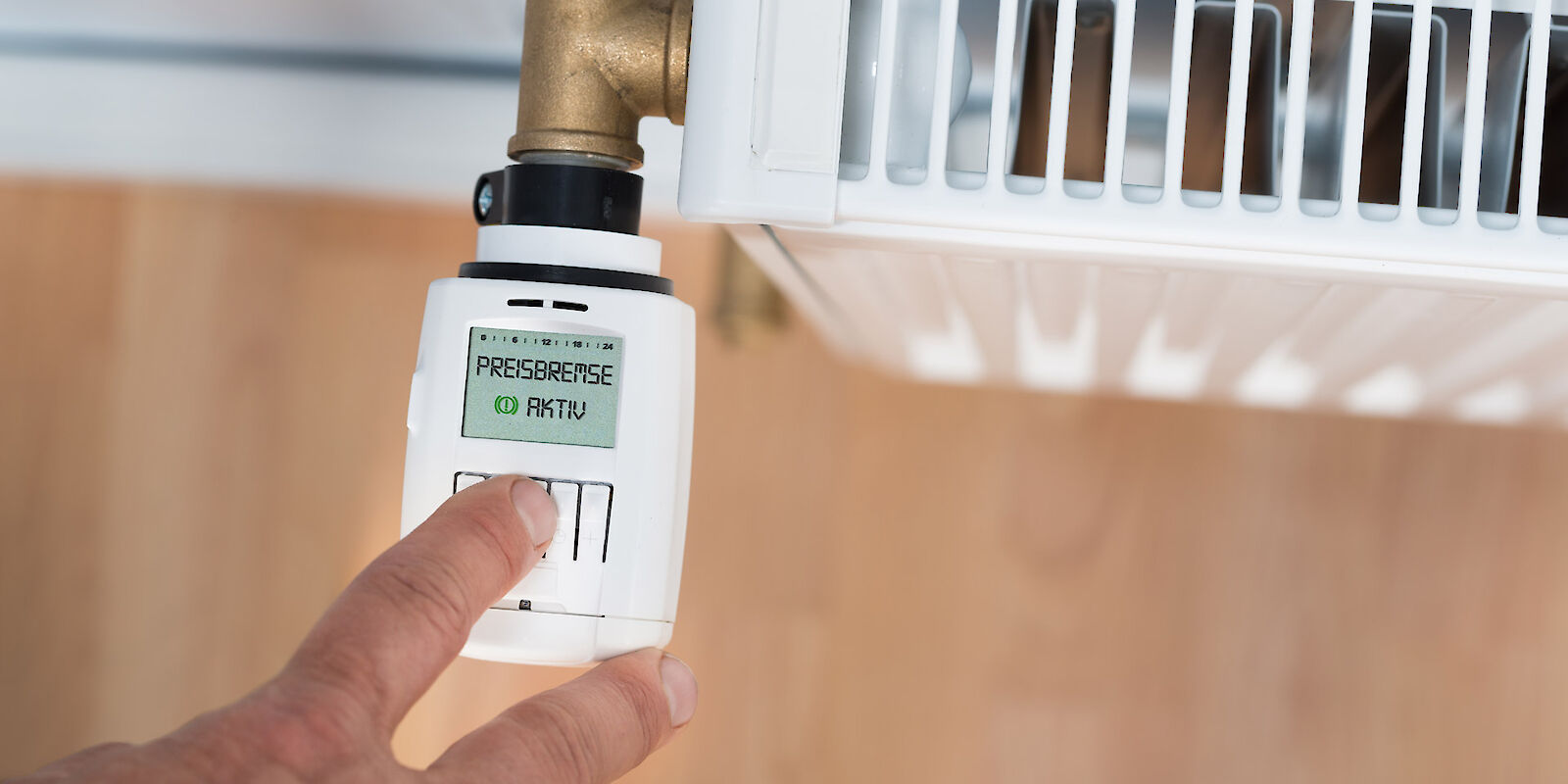 Ein Thermostat mit aktivierter Energiepreisbremse auf dem Display wird bedient.