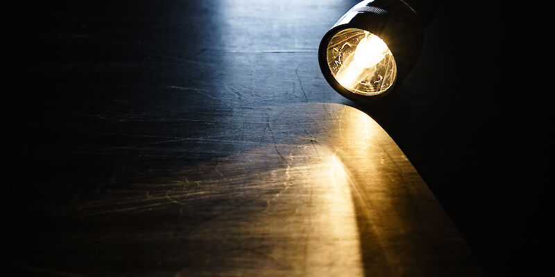 Eine Taschenlampe liegt angeschaltet auf einem Tisch